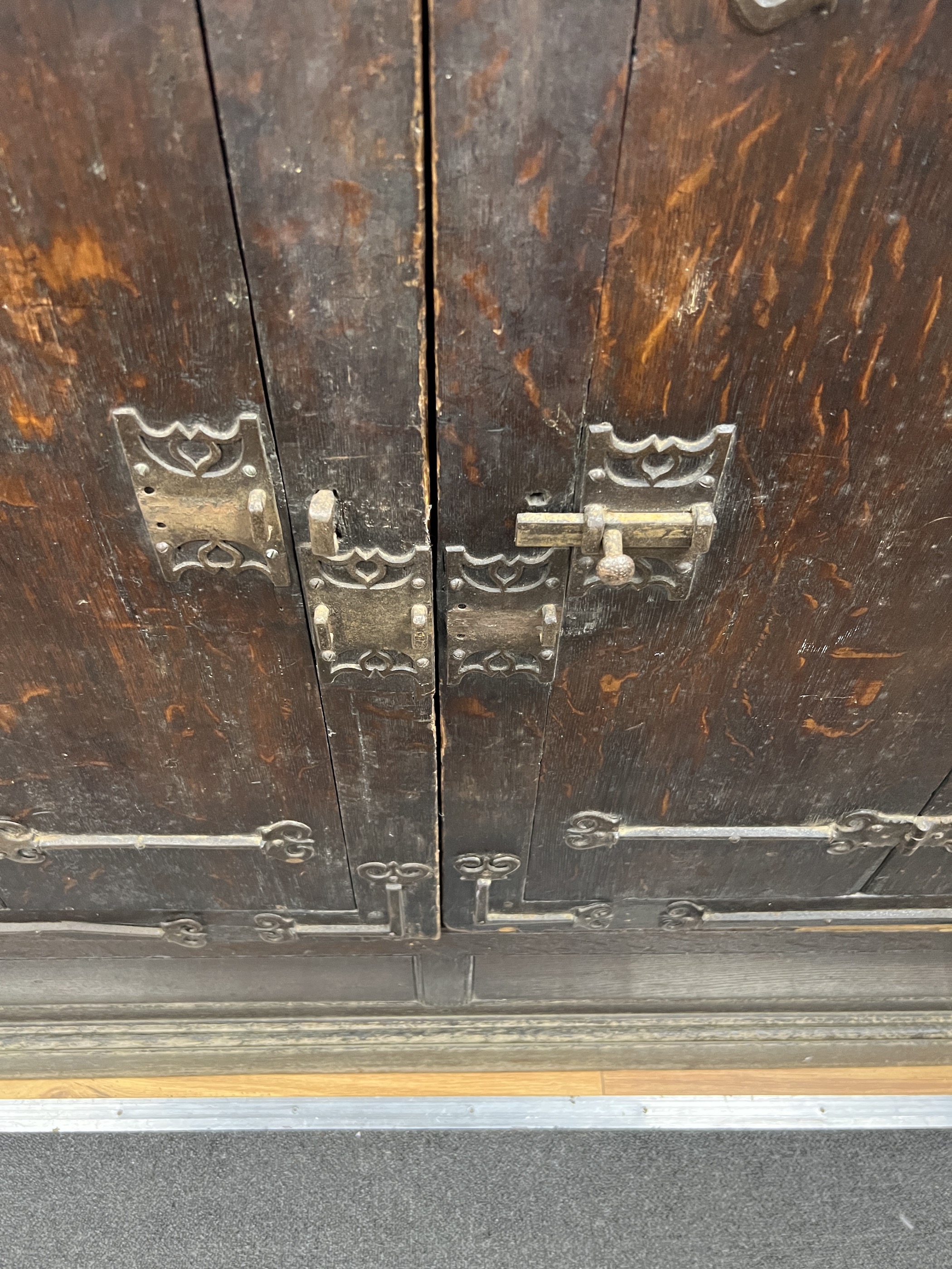 A pair of 16th century German or Netherlandish oak and wrought iron strapwork window shutters, later mounted on a cupboard, the moulded cornice above two pairs of hinged shutters, (previously bi-fold), mounted with elabo